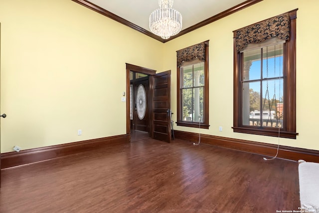 empty room featuring a notable chandelier, dark hardwood / wood-style floors, and crown molding