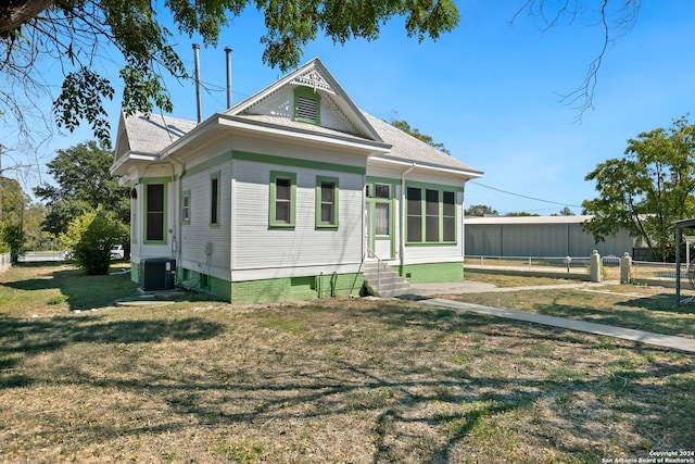 view of front of home with a sunroom, central air condition unit, and a front yard