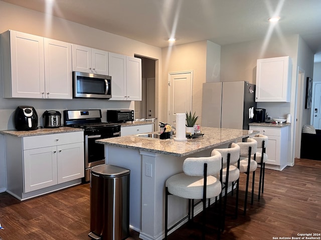 kitchen with a center island with sink, white cabinets, stainless steel appliances, and dark hardwood / wood-style floors