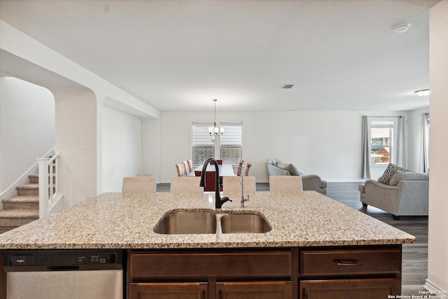 kitchen featuring sink, a kitchen island with sink, dishwasher, light stone countertops, and dark hardwood / wood-style flooring