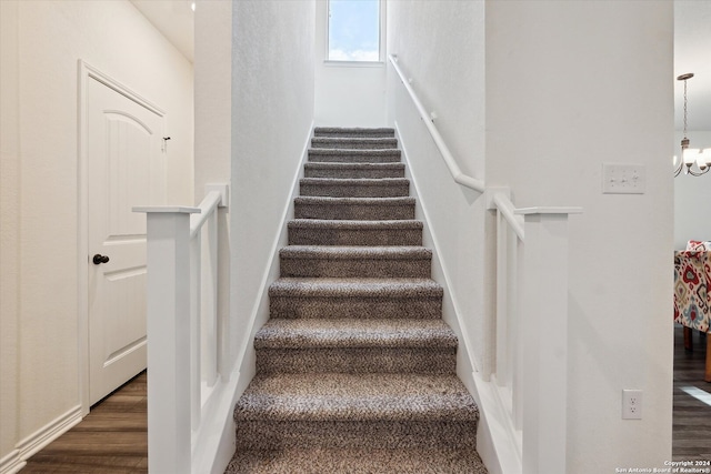 stairs with hardwood / wood-style flooring and a chandelier