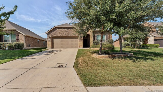 view of front facade with a garage, a front yard, brick siding, and driveway