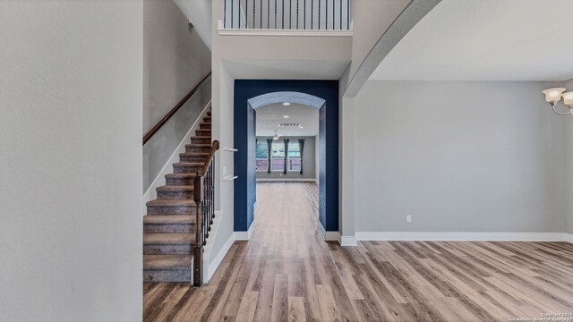 foyer featuring baseboards, arched walkways, and wood finished floors