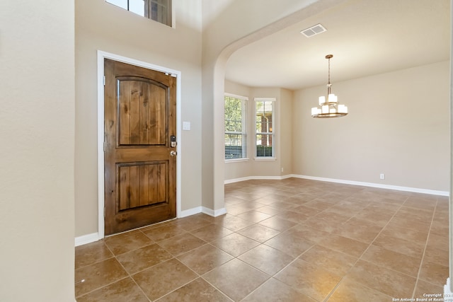 tiled entrance foyer featuring an inviting chandelier