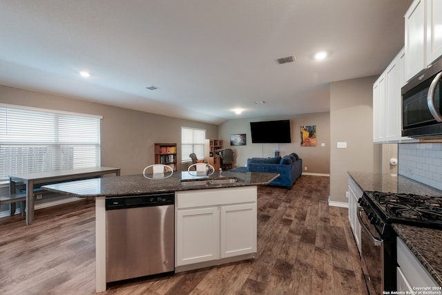 kitchen featuring dark wood-type flooring, dark stone counters, appliances with stainless steel finishes, and white cabinetry