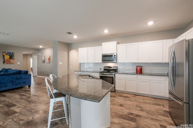 kitchen featuring a center island with sink, hardwood / wood-style flooring, stainless steel appliances, and white cabinets