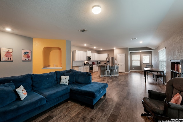 living room featuring lofted ceiling, dark wood-type flooring, and a textured ceiling