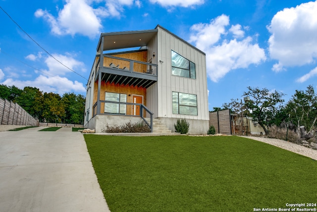 modern home with a balcony and a front lawn