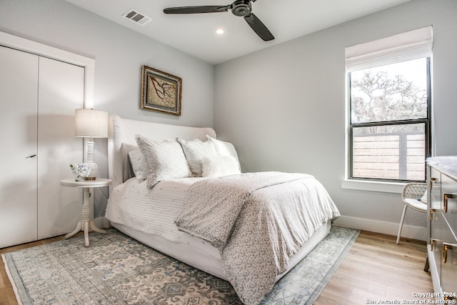 bedroom with a closet, light hardwood / wood-style floors, and ceiling fan