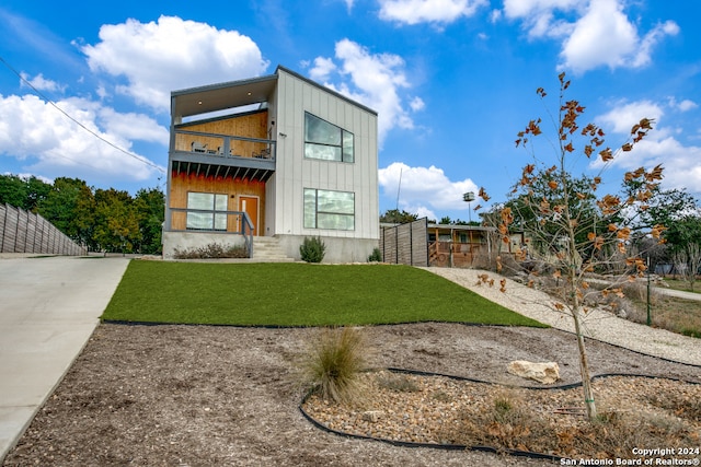 view of front of house featuring a balcony and a front lawn