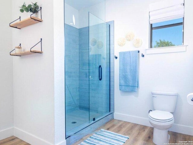 full bathroom with baseboards, wood finished floors, a tile shower, and toilet