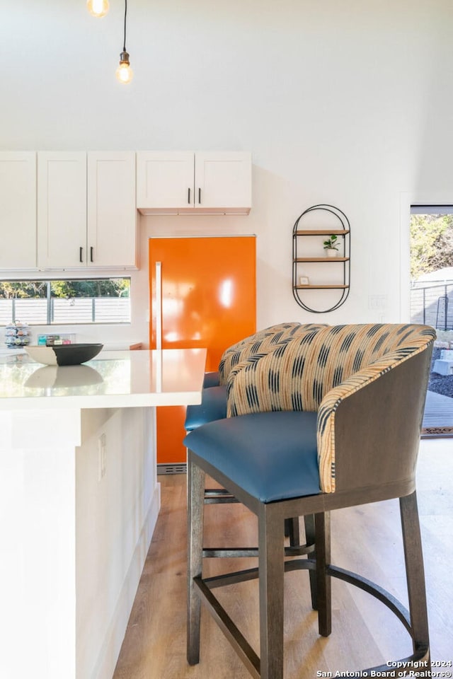 interior space featuring a kitchen breakfast bar, white cabinets, pendant lighting, and plenty of natural light