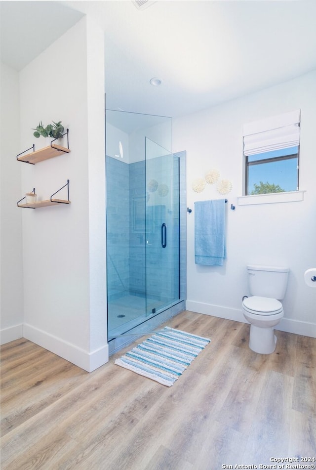 bathroom with a shower with door, hardwood / wood-style flooring, and toilet