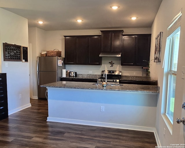 kitchen with stainless steel appliances, sink, dark hardwood / wood-style flooring, dark stone counters, and dark brown cabinets