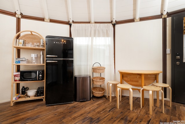 interior space with wood ceiling, beam ceiling, dark wood-type flooring, and black appliances