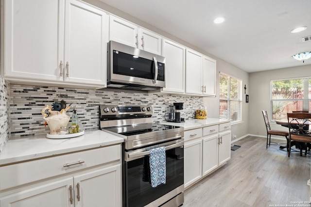 kitchen with appliances with stainless steel finishes, white cabinetry, and light stone counters