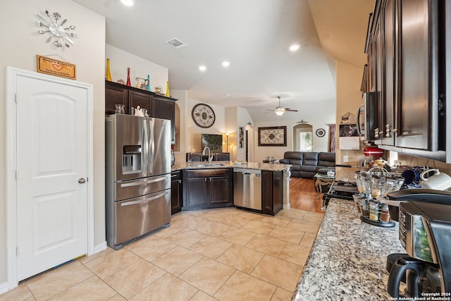 kitchen featuring light stone counters, ceiling fan, dark brown cabinetry, sink, and appliances with stainless steel finishes