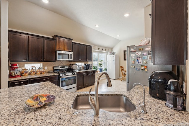 5018 Italica Rd, San Antonio, TX 78253 - kitchen featuring dark brown cabinets, light stone countertops, appliances with stainless steel finishes, a sink, and lofted ceiling