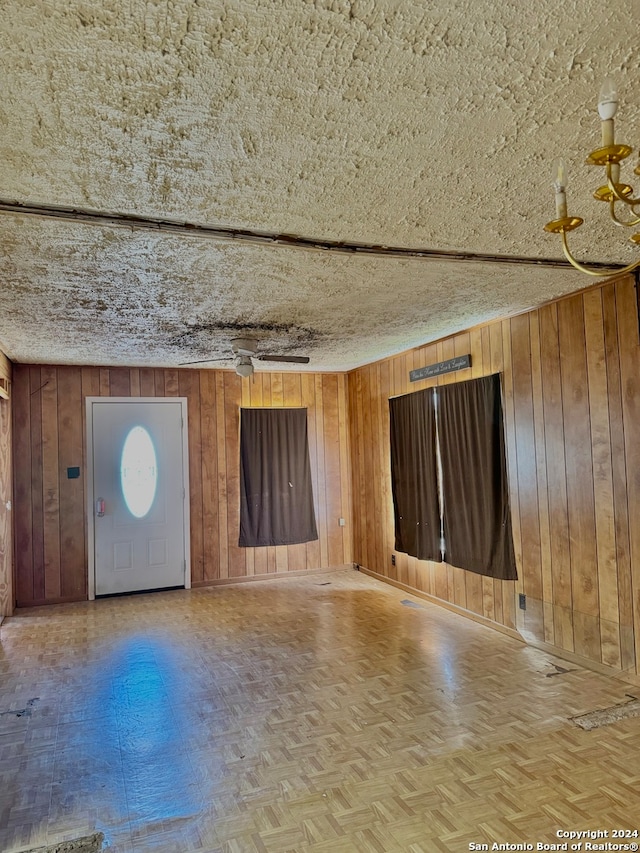 interior space featuring wood walls, parquet floors, and a textured ceiling