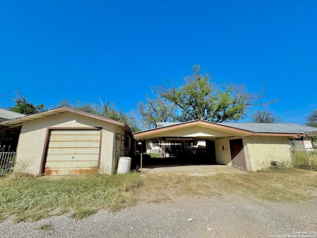 view of front of property with a garage, a carport, and an outbuilding