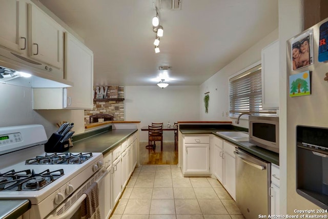 kitchen featuring white cabinets, sink, light tile patterned flooring, a fireplace, and appliances with stainless steel finishes