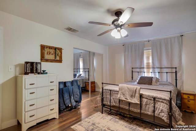 bedroom with dark wood-type flooring, a closet, multiple windows, and ceiling fan