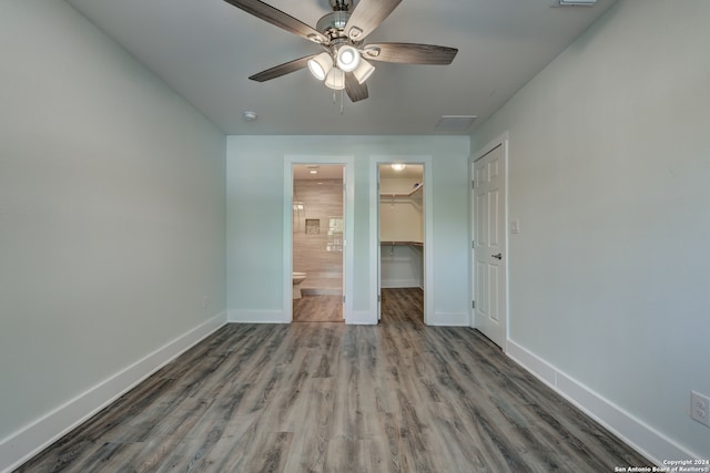 unfurnished bedroom featuring a walk in closet, ceiling fan, a closet, connected bathroom, and hardwood / wood-style flooring