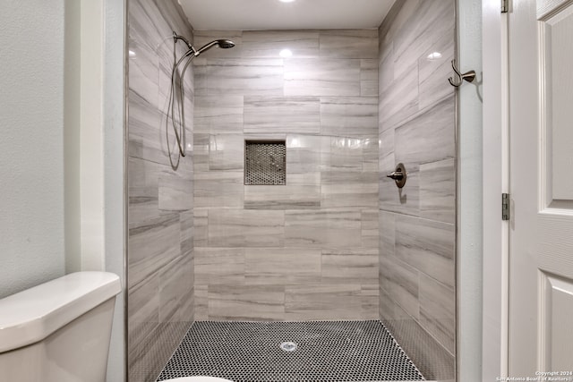 bathroom featuring tiled shower and toilet