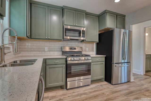 kitchen with appliances with stainless steel finishes, green cabinets, and light hardwood / wood-style flooring