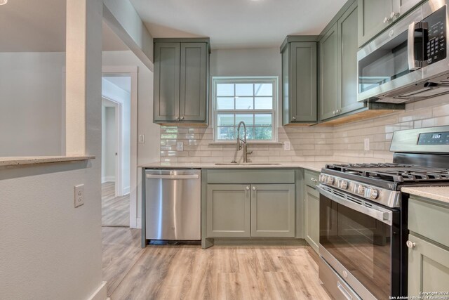 2293 W Mill St, New Braunfels, TX 78130 - kitchen with appliances with stainless steel finishes, a sink, green cabinets, light countertops, and decorative backsplash