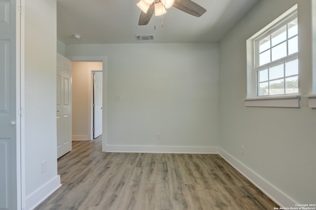 empty room with ceiling fan and light hardwood / wood-style flooring