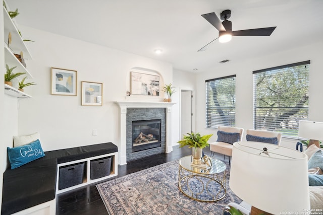 living room featuring ceiling fan, a stone fireplace, and dark hardwood / wood-style floors