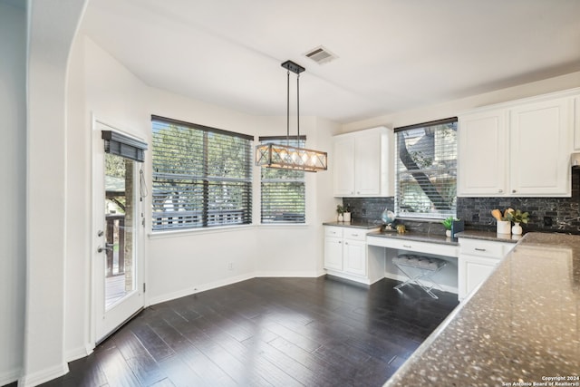 kitchen featuring dark wood-type flooring, dark stone countertops, decorative light fixtures, backsplash, and white cabinetry