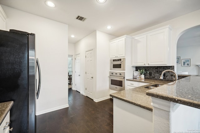 kitchen with dark hardwood / wood-style floors, sink, backsplash, white cabinets, and appliances with stainless steel finishes