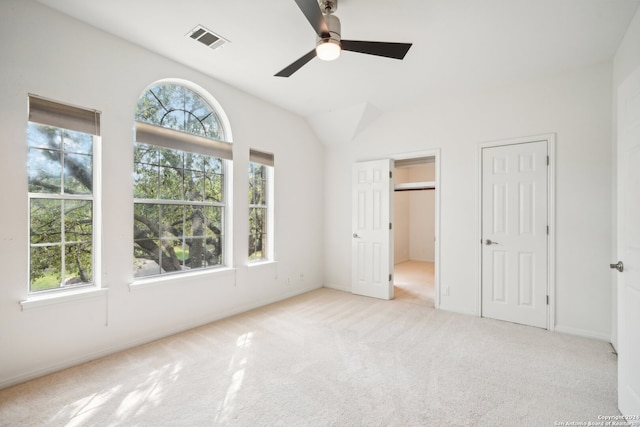 unfurnished bedroom featuring ceiling fan, multiple closets, and light carpet