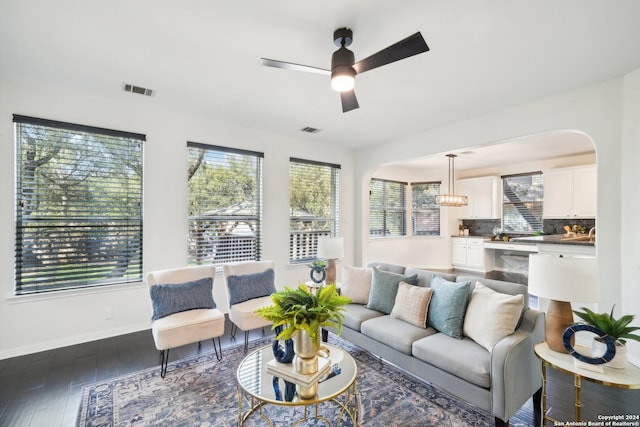 living room with ceiling fan with notable chandelier and dark wood-type flooring