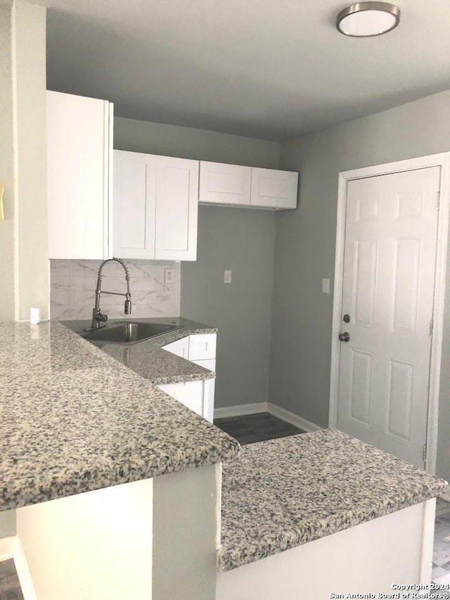 kitchen featuring decorative backsplash, sink, stone counters, and white cabinets