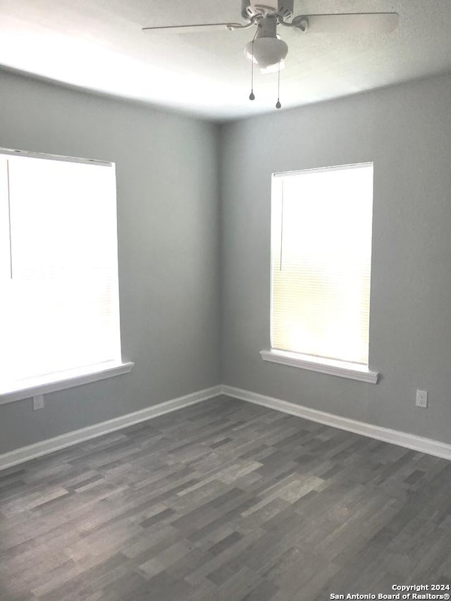 unfurnished room featuring ceiling fan, dark hardwood / wood-style floors, and a healthy amount of sunlight