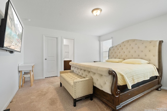 bedroom with light colored carpet, baseboards, and ensuite bath