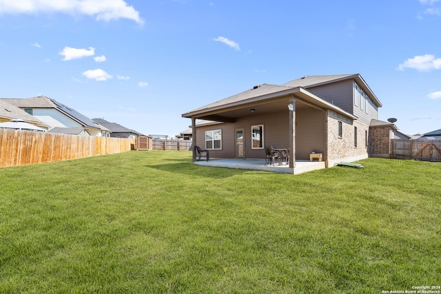 back of property featuring a fenced backyard, a yard, a patio, and a storage unit