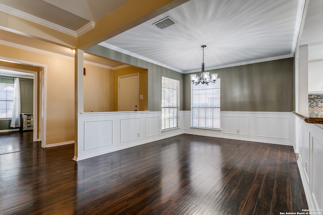 unfurnished dining area with ornamental molding, a wealth of natural light, dark wood-type flooring, and a chandelier