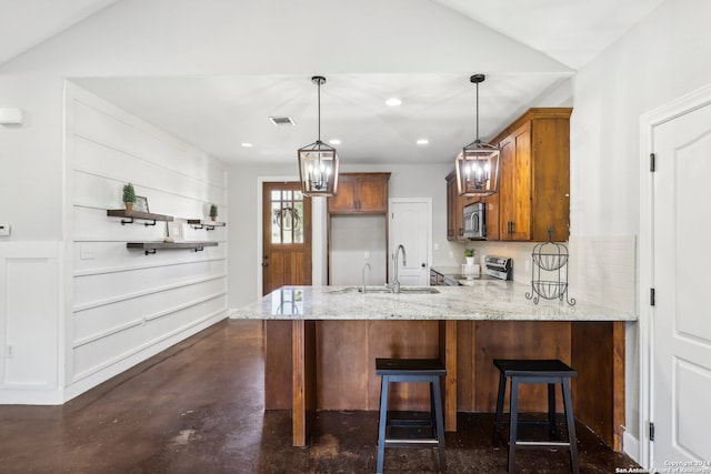 kitchen featuring sink, kitchen peninsula, decorative light fixtures, stainless steel appliances, and a breakfast bar