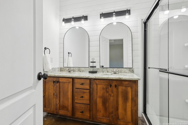 bathroom with wood walls, a shower with shower door, and vanity