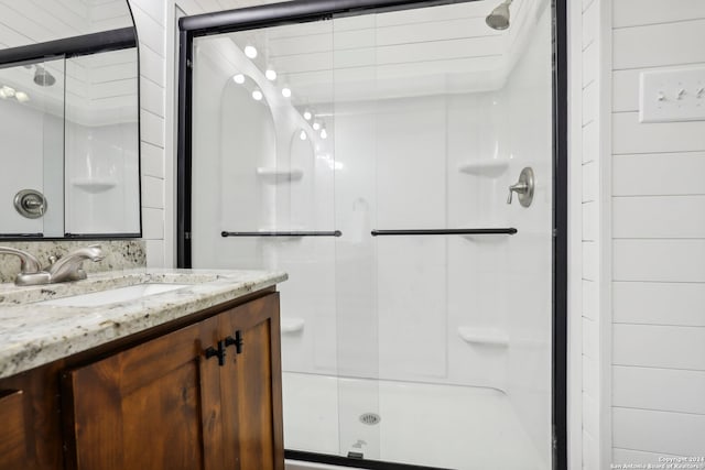 bathroom featuring a shower with door and vanity