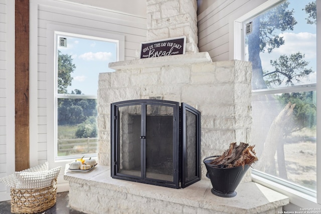 room details featuring wooden walls and a stone fireplace