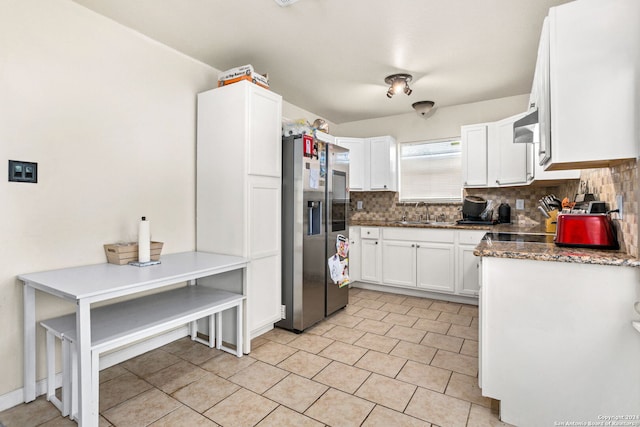 kitchen with dark stone counters, sink, backsplash, stainless steel refrigerator with ice dispenser, and white cabinetry