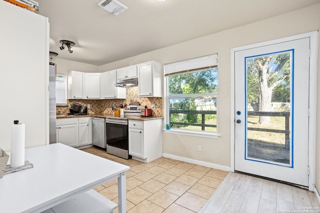 kitchen with white cabinets, stainless steel appliances, light hardwood / wood-style flooring, and decorative backsplash