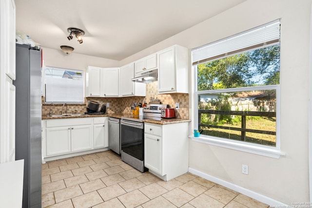 kitchen with appliances with stainless steel finishes, plenty of natural light, and white cabinets