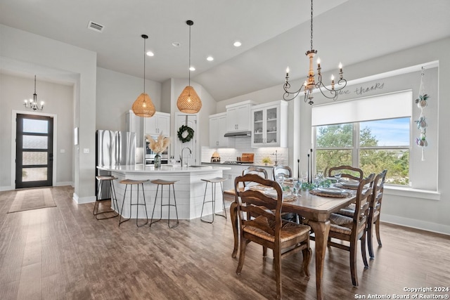 dining room with an inviting chandelier, lofted ceiling, sink, and light hardwood / wood-style flooring