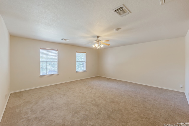 carpeted empty room with ceiling fan and a textured ceiling